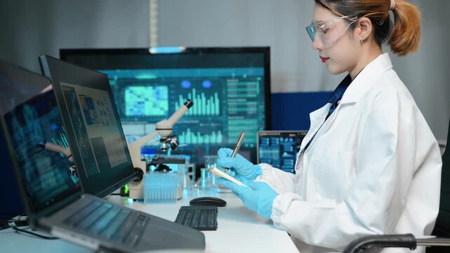 Female scientist examining a test tube and taking notes in a futuristic laboratory. She analyzes medical or biotech samples alongside high tech digital