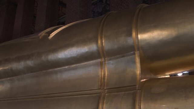 close perspective of the colossal golden reclining buddha statue inside the historic temple hall at wat pho in bangkok thailand