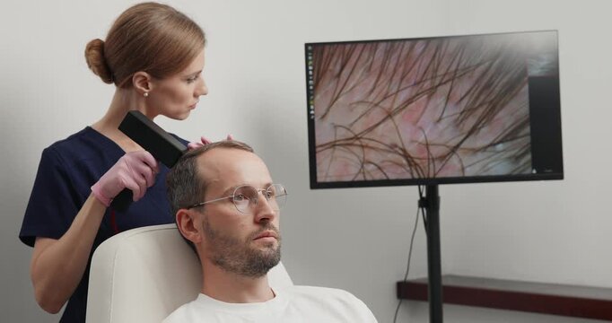 Closeup male scalp treatment with handheld laser device at hair clinic for thinning hair examination and medical consultation.