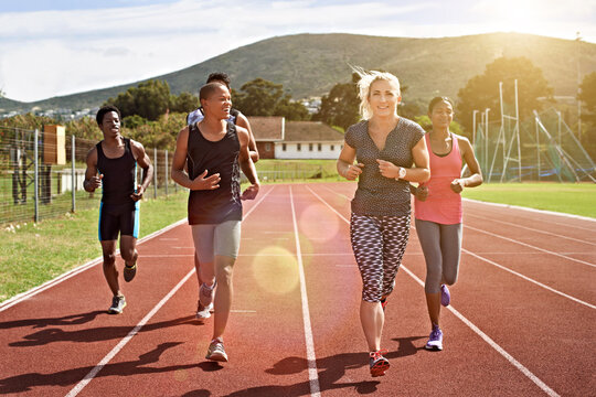 Coach, teenager and students running on track with speed training, guidance and athletics practice. Bokeh, woman and young happy people outdoor with exercise, fitness and teacher for school athlete.