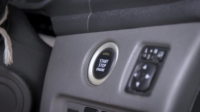 Close up of a hand pressing the engine start button inside a car