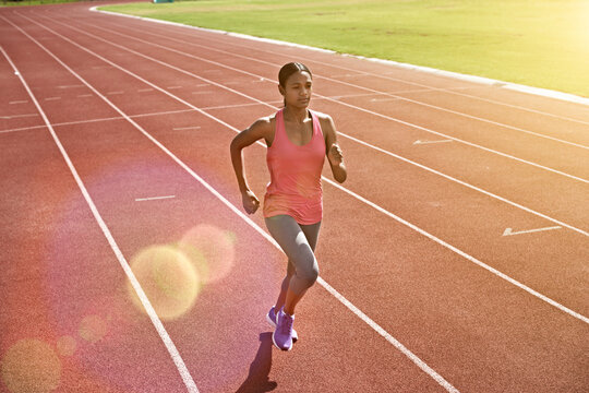 Fitness, woman and college student running on track with speed exercise, cardio training or practice. Bokeh, person and athlete outdoor at university with sports scholarship, workout and wellness.