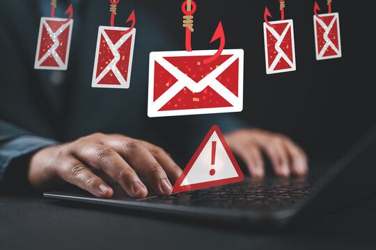 Phishing email scams and personal information theft. Hooked email icon. Warning triangle icon with exclamation mark. Man using laptop computer to open and respond to emails.