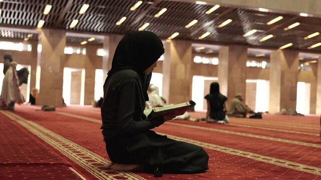 Muslim woman reading the quran inside a mosque