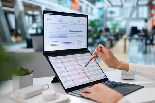 Young Woman Uses Dual Touchscreen Laptop Analyzing Sales Data