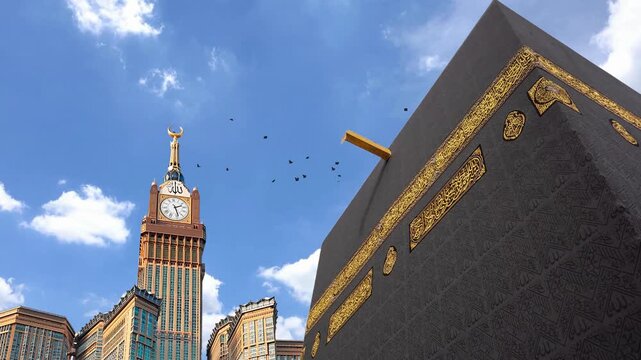 Close up view of the Kaaba at Masjid al Haram in Mecca, Saudi Arabia, featuring its black Kiswah with intricate golden Arabic calligraphy and the Makkah Royal Clock Tower in the background 