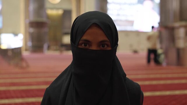 Muslim woman in niqab looking at camera inside mosque
