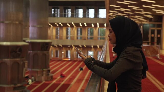 Muslim woman using smartphone inside mosque