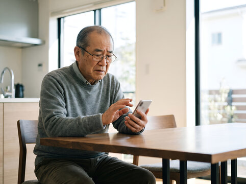 Elderly Asian man hesitating before tapping suspicious phone link
