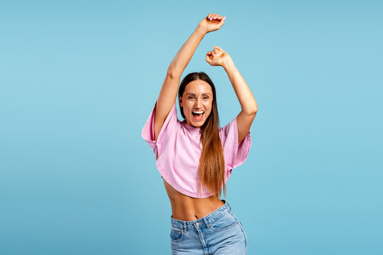 Happy young woman celebrating victory with raised arms