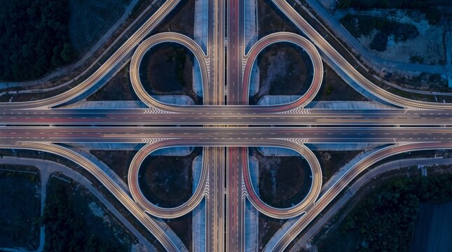 Aerial top view of cloverleaf highway interchange with night traffic light trails