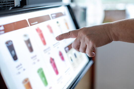 Selective focus to Customer using self service kiosk interactive touchscreen display to order drinks in coffee shop