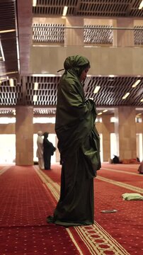 Muslim woman performing daily islamic prayer inside mosque