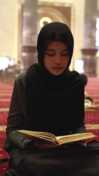 Muslim woman in hijab reading the quran