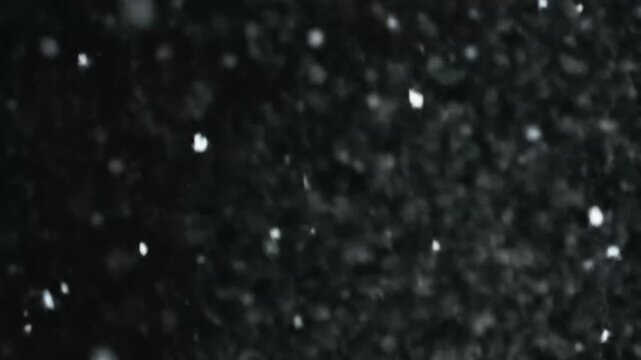 Abstract white particles scattering on a deep black background