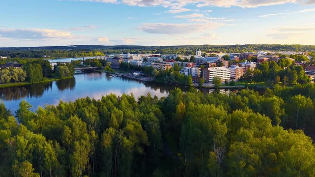 City reveal behind trees in aerial drone footage in H&auml;meenlinna Finland. 