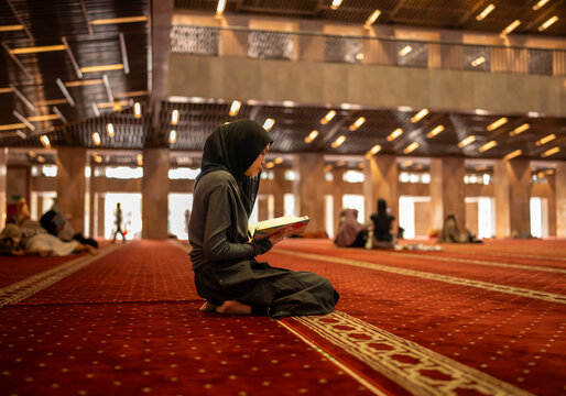 Muslim woman reading quran in mosque praying