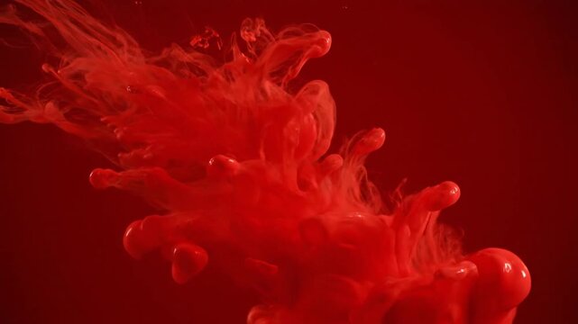 Vibrant red liquid ink spreading in abstract organic fluid shape