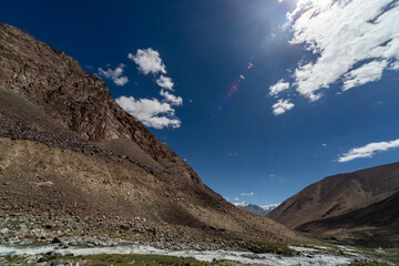 Rocky mountain valley with stream under deep blue sky © Ruslan Bolgov