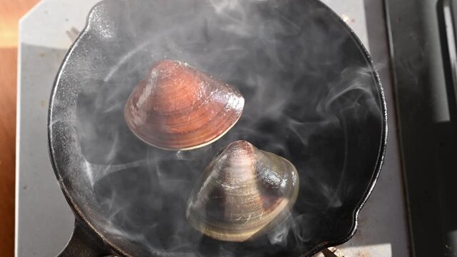 網焼きでぐつぐつと沸騰する醤油と湯気が立つ大粒のハマグリ