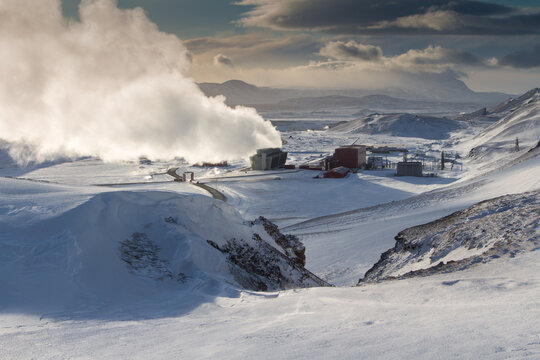 Steam, vapour, blue skies and sunny mountain landscape Krafla geothermal power plant  , north Iceland. Fuming winter nature.
