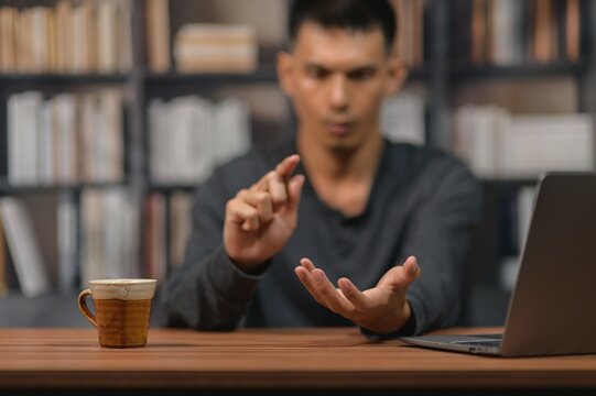 Man with focused expression working on laptop with coffee mug in a library setting