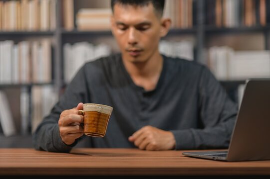 Young Man Relaxing at Library with Coffee and Laptop in Modern Study Room