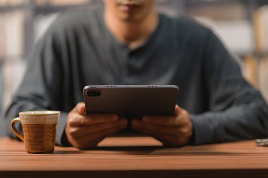 Person Using a Smartphone with a Coffee Mug on a Wooden Table in a Cozy Environment
