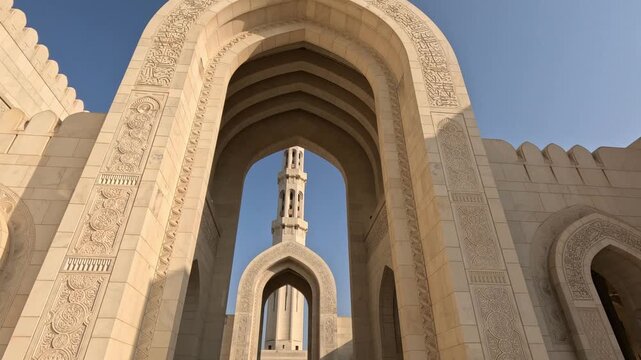 Wide shot showing the entrance arch of Sultan Qaboos Mosque in Oman with smooth camera movement capturing its grand architectural design during daytime.