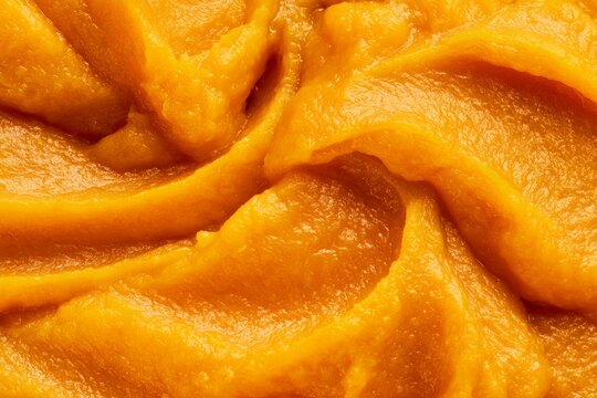Bright orange pureed food served in a bowl during meal preparation in a kitchen