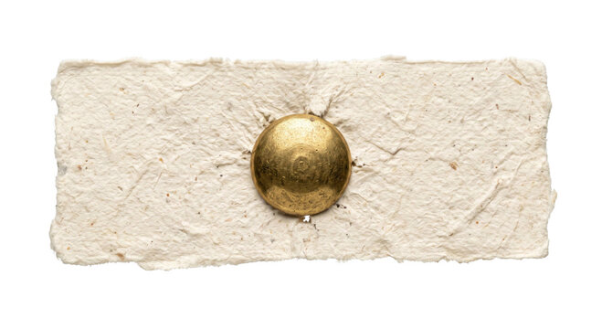 Close-up of a golden tack securing rough textured handmade paper