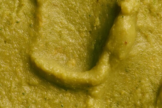 Green paste sits in a bowl, made from blended ingredients, prepared for a meal in a kitchen