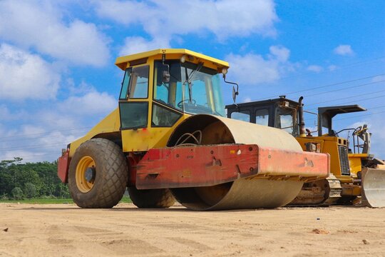 road roller with yellow color, on construction site and sky background