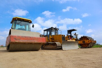 bulldozer and road roller with yellow color, on construction site and sky background © faiz