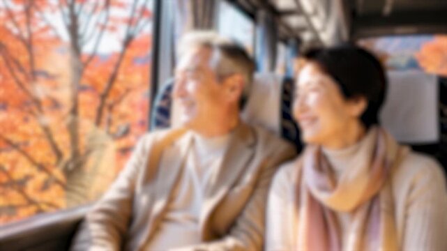 ぼかし背景素材: 観光バスに乗って窓から紅葉を眺めながら微笑み合うシニア夫婦　バス旅、紅葉狩り、アクティブシニアのイメージ