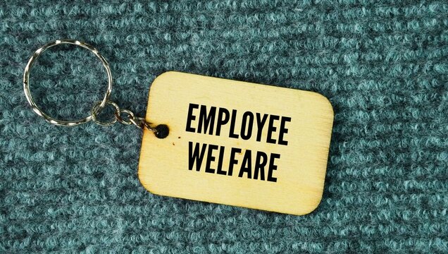 Wooden keychain with the word Employee welfare. the extra services, benefits, and support systems that an employer provides to improve workers' physical, mental, and financial well-being beyond their 