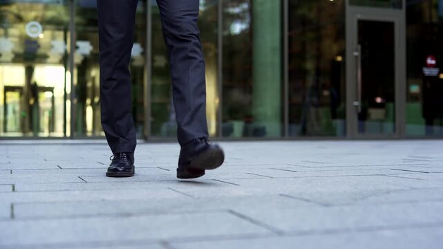 Front view close up of businessman legs stepping along urban street outside modern office building. Professional entrepreneur in formal suit walking on sidewalk to work. Executive male walking city.