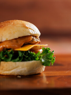 Delicious cheeseburger layer with golden bun juicy meat beef or pork patty melted cheddar cheese on wooden table background fresh ingredients green lettuce tomatoes tasty classic burger junk fast food