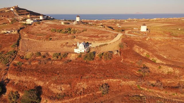Aerial drone shot of historic windmills and chapel on Gavrilos Hill at sunrise Emporio Santorini Greece