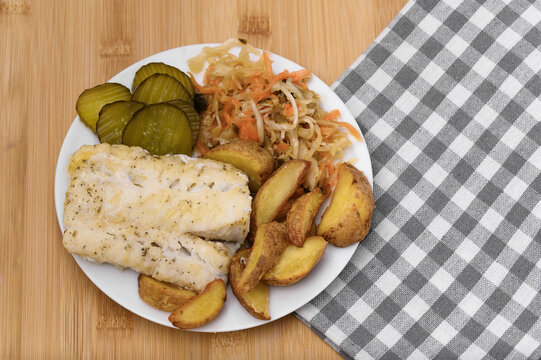 Homemade dinner on a plate, cod fish with salad and baked potatoes