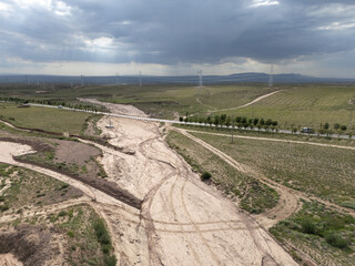 Naklejka premium Muddy dry riverbed and dirt road after heavy rain on the grassland plains