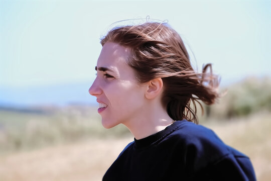 A beautiful young woman in the field, looking away