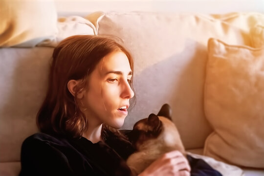 A young woman lying on the couch with her cat.