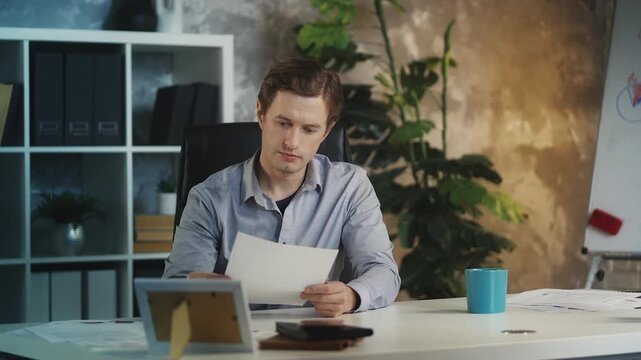 Young male business analyst checks documents in office, reviewing contracts