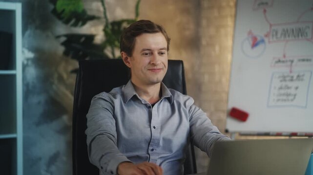 Young business analyst completes project on laptop, pleased with work result