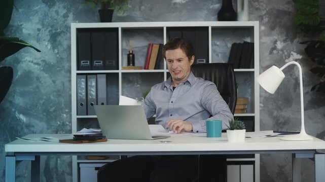Young male boss throws papers in air, upset about company bankruptcy in office