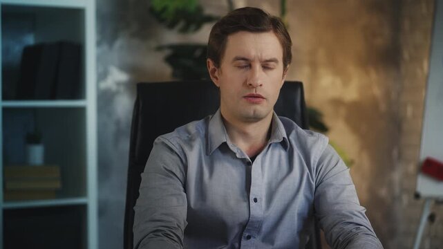 Exhausted young businessman closes laptop, stressed by heavy workload in office