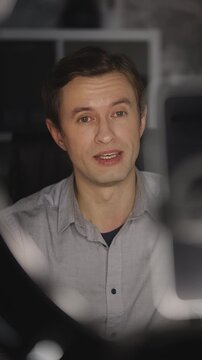 Successful young man records video blog on phone, teaching how to earn money