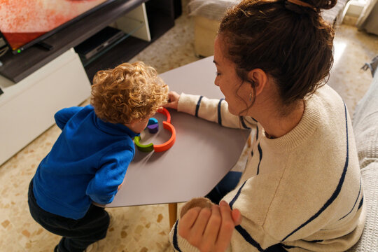Mother and young son playing together with a colorful wooden puzzle toy, focusing on learning and development