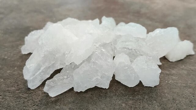 Natural white alum crystal stones on a textured concrete surface. Ideal for natural deodorant, body care, cosmetics, and water purification concepts